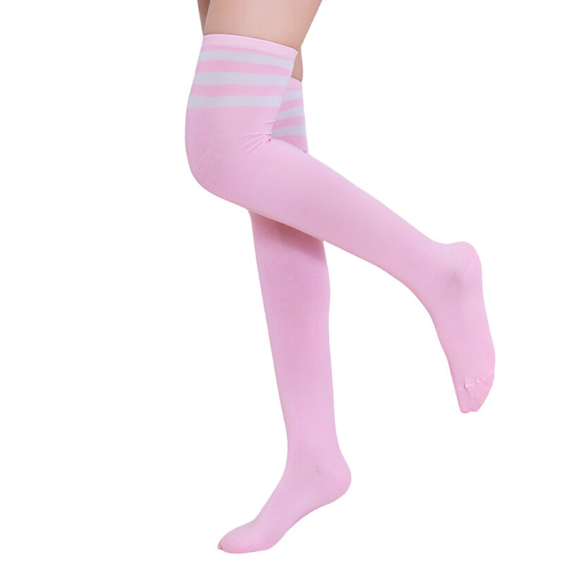 Medium shot of pink striped thigh-high socks from Femzai, perfect for a playful and vibrant femboy clothing ensemble. The socks are presented against a simple indoor background, emphasizing their soft pink hue with contrasting lighter pink stripes at the elastic band.