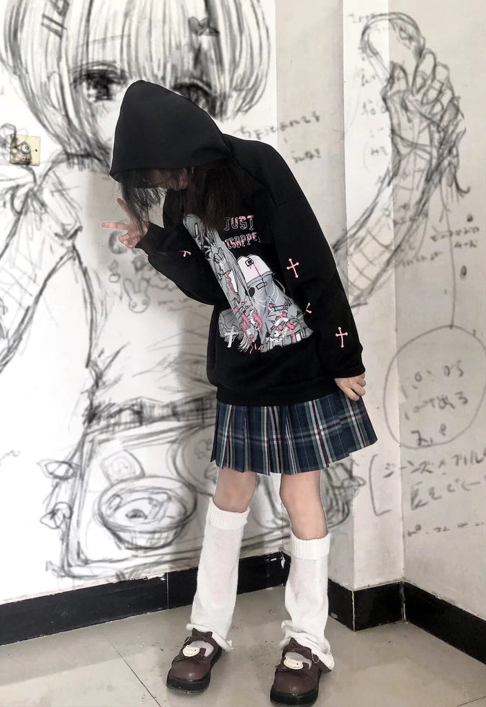 Close-up shot of a person in a mysterious pose wearing a Femzai 'Just Disappear' black graphic hoodie with anime-style print, paired with a plaid pleated skirt and white knee-high socks, showcased in a creative space with hand-drawn sketches, embodying alternative femboy clothing style.