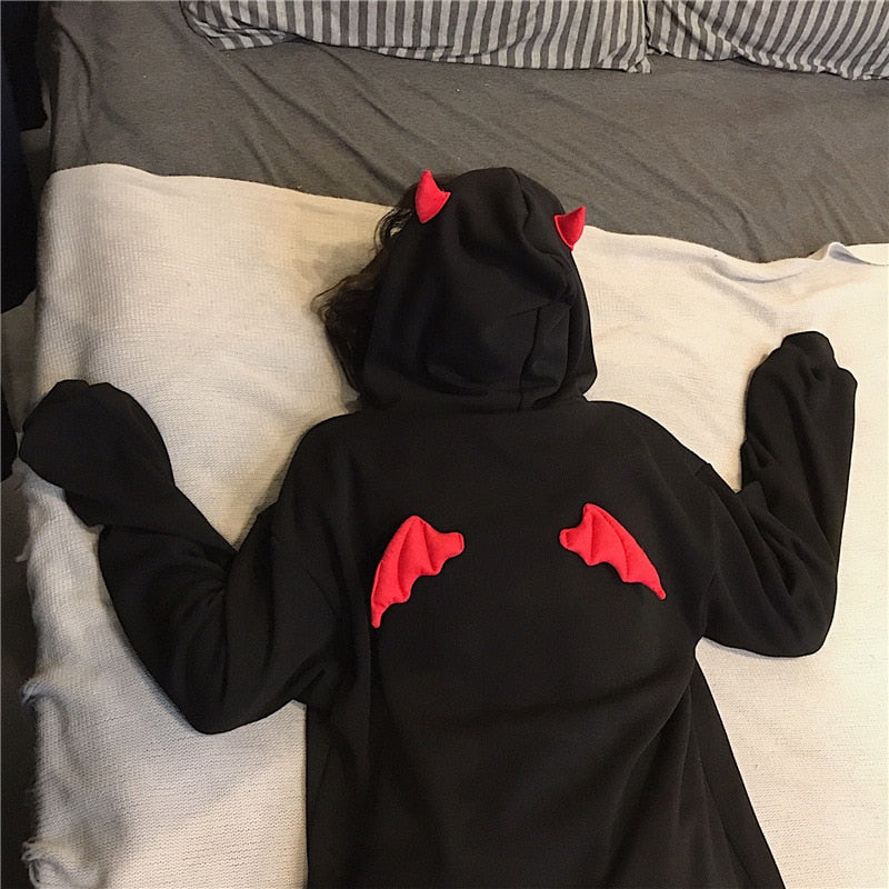 Top view close-up of black oversized hoodie with devil horns design from Femzai, displayed on a white bed - femboy clothing style.