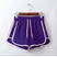 Hanging view of a purple dolphin short with white contrasting side stripes and adjustable drawstrings, displayed on a wooden hanger against a white backdrop.