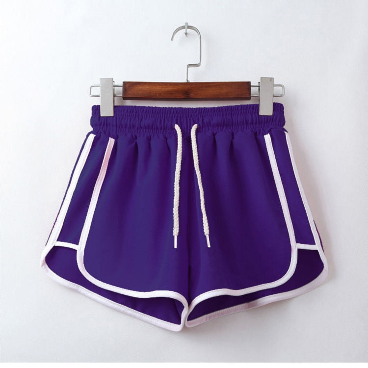 Hanging view of a purple dolphin short with white contrasting side stripes and adjustable drawstrings, displayed on a wooden hanger against a white backdrop.