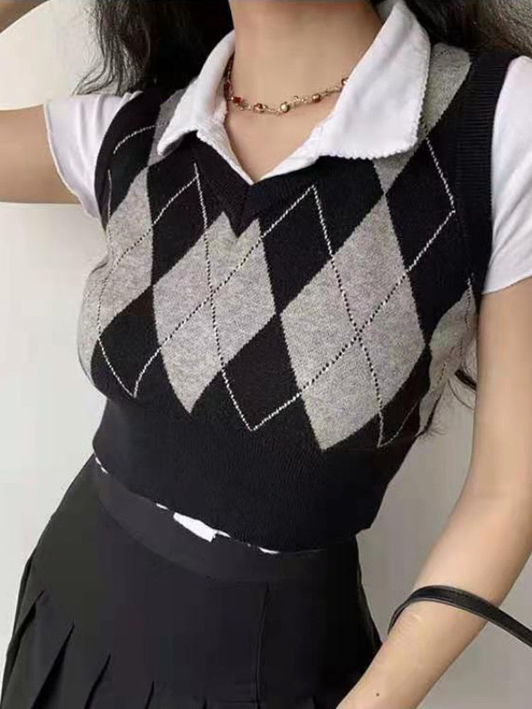 Close-up shot front view of a model donning a black and grey Femzai Gridded V-neck Vest with a white collar, paired with a black pleated skirt, accentuated by a gold chain necklace, ideal for sophisticated daily wear.