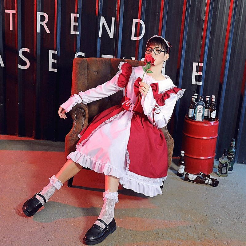 Image Description: Femzai's red and white maid dress product displayed in a medium shot. The model, adorned with glasses and a complementary maid headband, sits poised on a vintage brown chair holding a rose. The red curtains in the backdrop feature "TREND CASES", and various beverage bottles rest beside a red barrel on the ground.