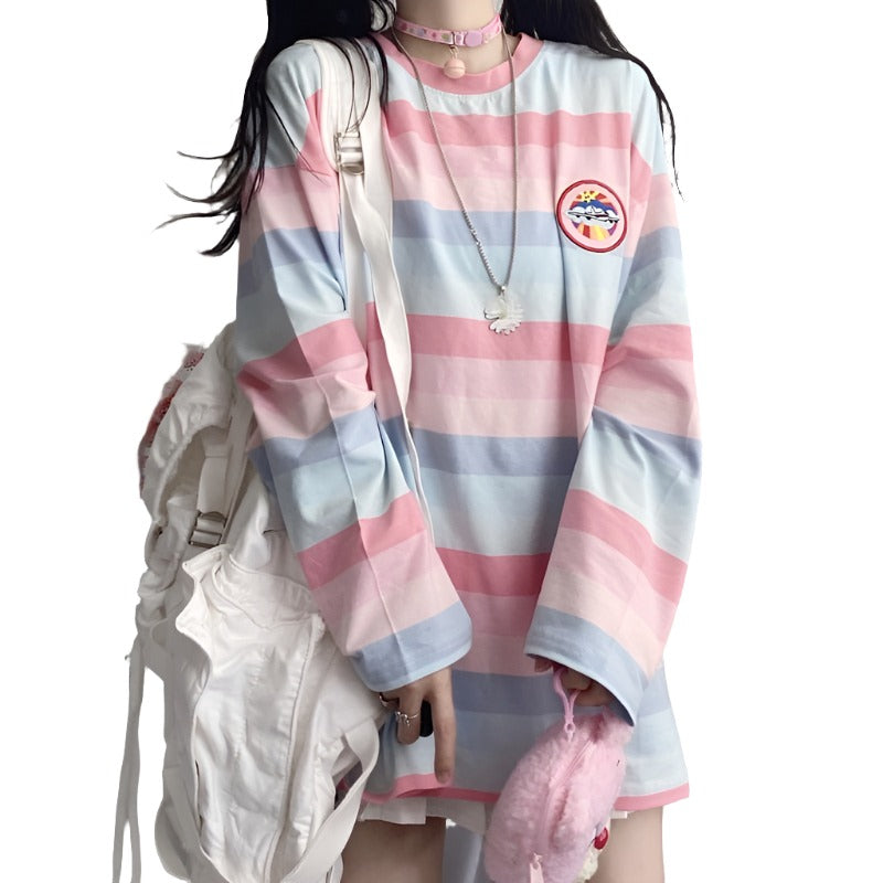 Close-up shot of a model wearing a pastel-colored Femzai striped oversized shirt with a front view, displaying the shirt's logo and accessories against a textured backdrop, ideal for soft aesthetic clothing.