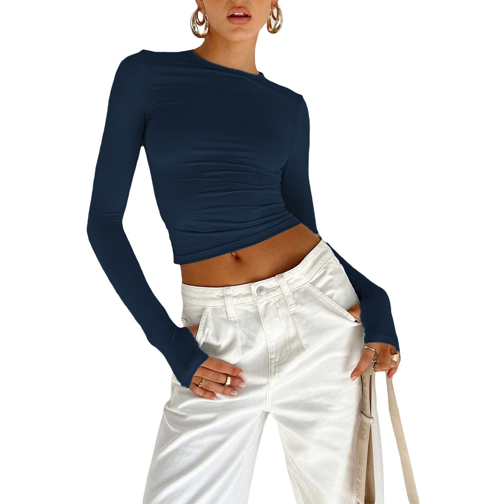 Medium shot frontal view of a model presenting a navy blue Femzai long-sleeve ruched top coupled with high-waisted white jeans, capturing a sophisticated urban look.