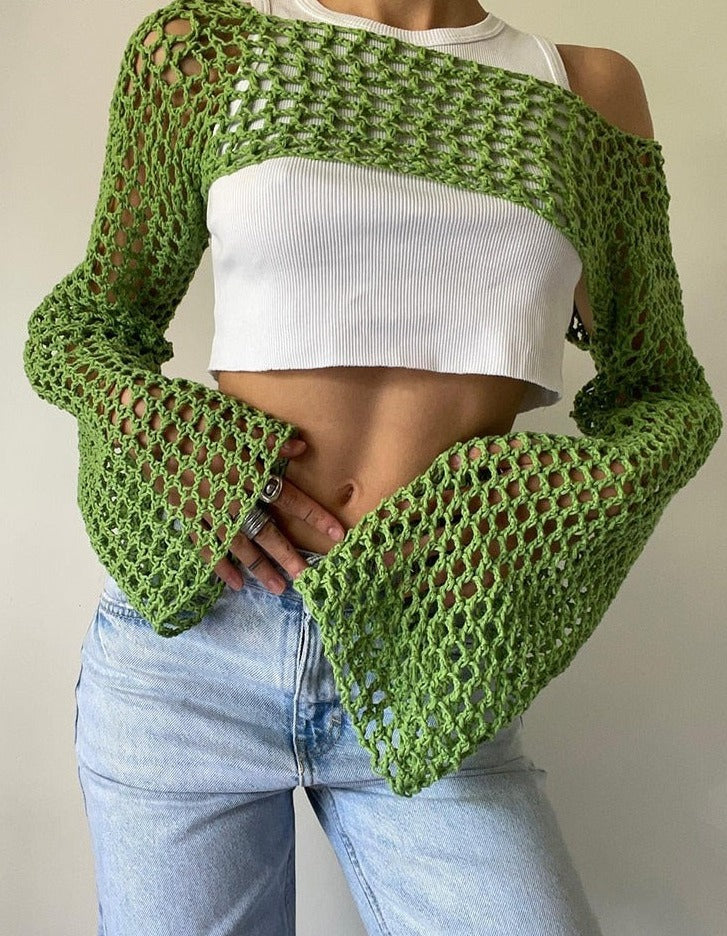 Close-up front view product shot showcasing a bold green crocheted Femzai long-sleeve overlay with detailed meshwork, complemented by a white cropped top and classic blue jeans, highlighting the distinctive femboy clothing aesthetic.