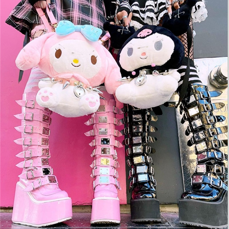 Femzai Store Product: Femboy clothing - Pastel pink and glossy black Demonia platform shoes with multiple buckles, accessorized with plush toys against a vibrant pink backdrop.