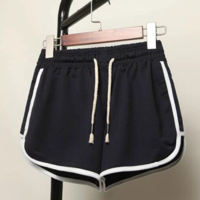 Display shot of classic black dolphin shorts with white trim, hanging view, prominently featuring adjustable drawstrings. A staple piece for femboy clothing collections