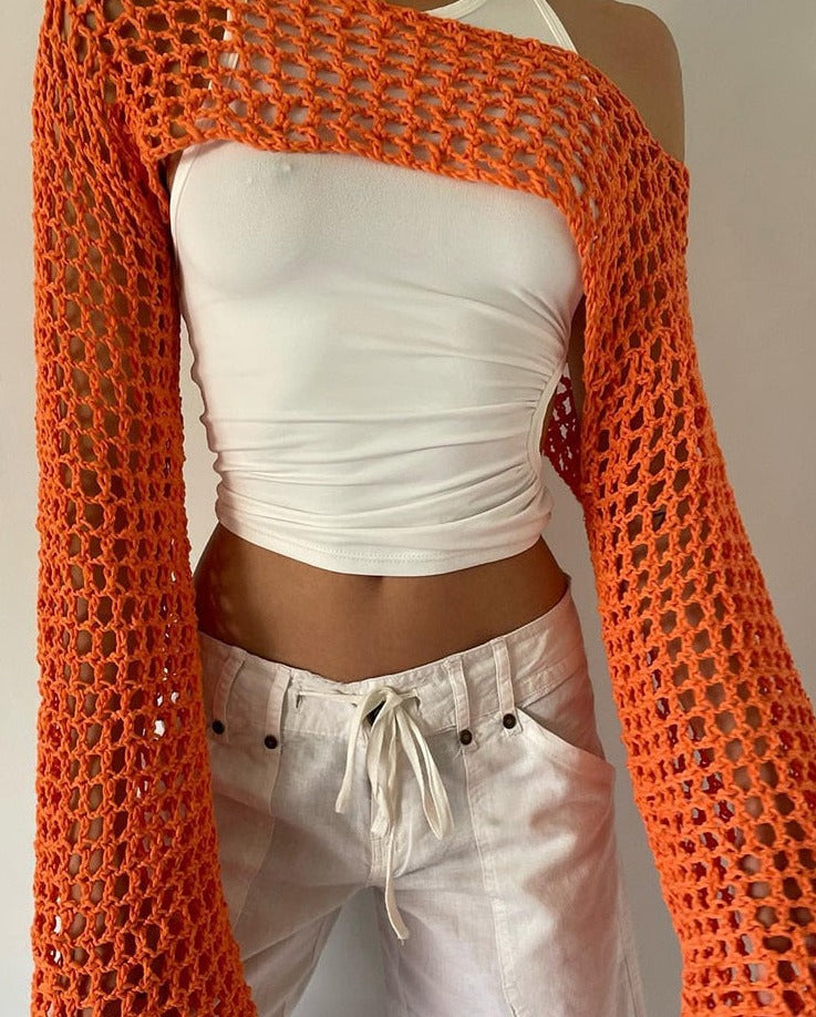 Close-up side view product shot showcasing a vibrant orange crocheted Femzai top with a distinct meshwork pattern. It's paired with a snug-fitting white tube top and complemented by light-colored jeans with a drawstring waist, highlighting the Femzai design ethos and femboy fashion statement.